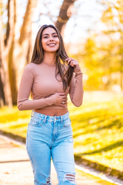 Lebensstil, Porträt eines kaukasischen Modells mit rosa Pullover und Jeans, die im Herbst in einem Park spazieren gehen