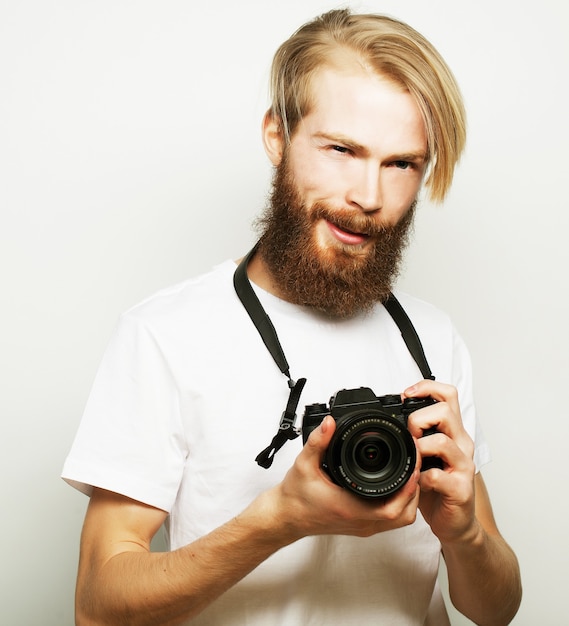 Lebensstil, Technologie und Reisekonzept: bärtiger Mann mit weißem T-Shirt mit einer auf weißem Hintergrund isolierten Digitalkamera