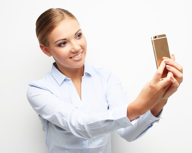 Lebensstil, Tehnologie und Personenkonzept: Schöne junge Frau macht Selfie-Foto mit Smartphone.