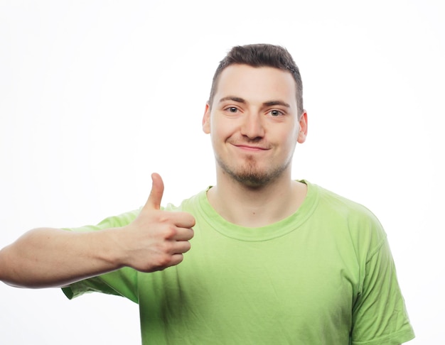 Lebensstil und Personenkonzept: glücklicher junger Mann im grünen Hemd, das sich Daumen zeigt. Getrennt auf Weiß.