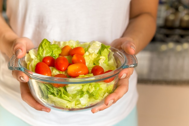 Lebensstile und Biokostkonzepthände, die organischen Salat halten, schlagen in der Küche durch.