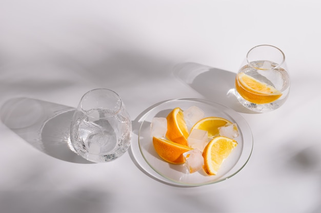 Lebensstilfoto mit Glasbechern mit frischem kaltem Wasser und Orangenscheibe