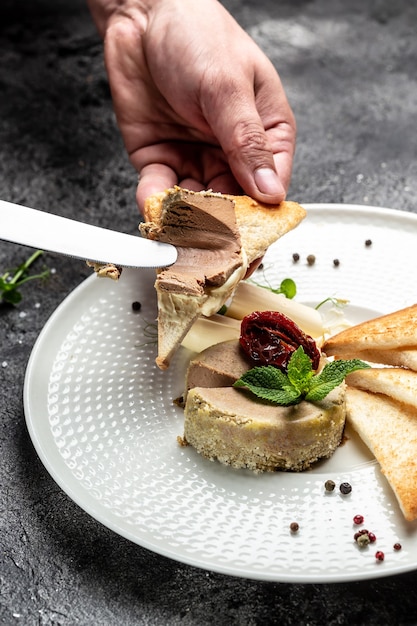 Leberpastete. Männliche Hände schmieren hausgemachte Paste auf geröstetem Brot. Frische hausgemachte Pastete. Hintergrund für Lebensmittelrezepte. Nahaufnahme.