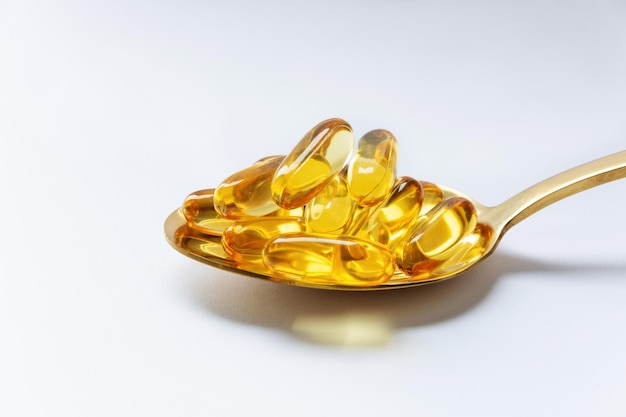 Lebertran Omega 3 Gelkapseln auf einem Löffel auf weißem Hintergrund