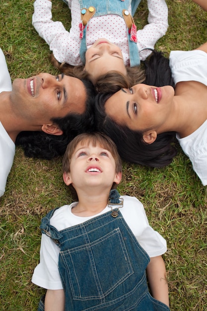 Lebhafte Familie, die in einem Kreis auf dem Gras liegt