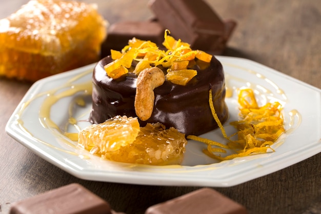 Lebkuchen com pedaços de damasco acima em um prato e chocolates e um pedaço de favo de mel sobre uma superfície de madeira.