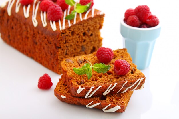 Lebkuchen (Honigkuchen) mit Rosinen, die mit Zuckerguss, Minzblättern und Himbeeren dekoriert sind