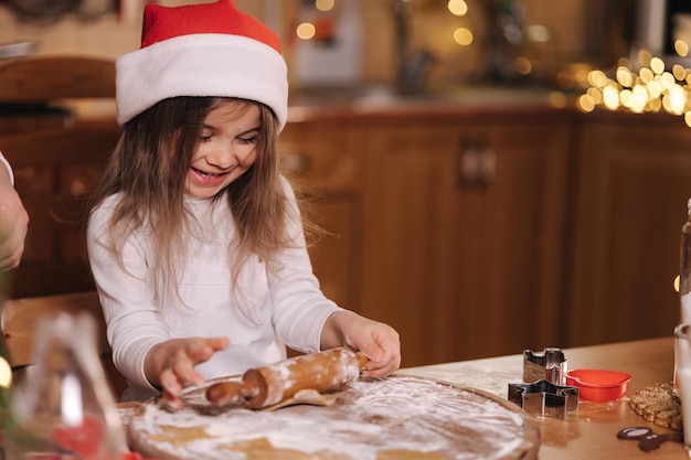 Lebkuchen zu Hause machen kleines Mädchen, das Kekse aus Lebkuchenteig schneidet Weihnachten und Neujahr