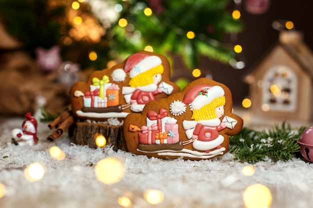 Lebkuchen zwei Chirstmas Briefträger und Schlitten mit Geschenken in gemütlicher warmer Dekoration mit Girlandenlichtern