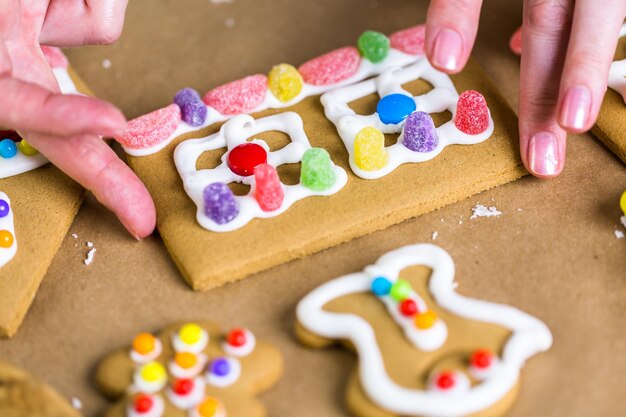 Lebkuchenhaus mit königlichem Zuckerguss und bunten Bonbons dekorieren.