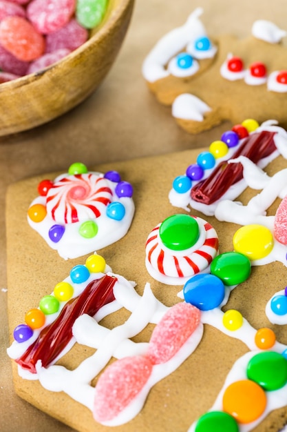 Lebkuchenhaus mit königlichem Zuckerguss und bunten Bonbons dekorieren.