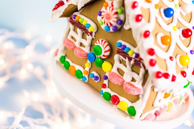 Lebkuchenhaus verziert mit weißer königlicher Zuckerglasur und hellen Bonbons.