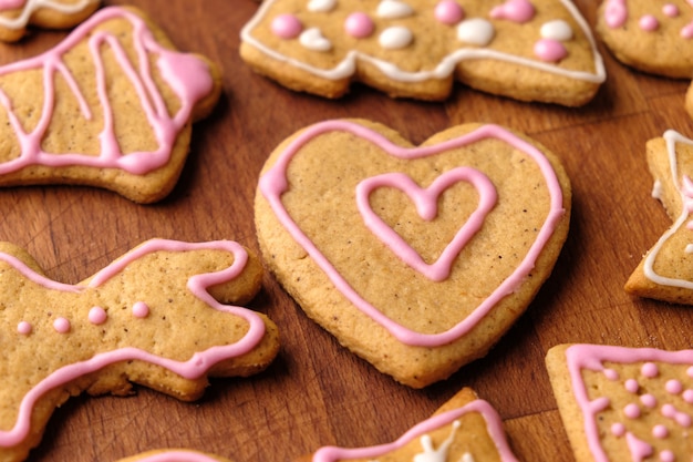 Lebkuchenherz zum Valentinstag auf dem Holztisch mit anderen hausgemachten Keksen.