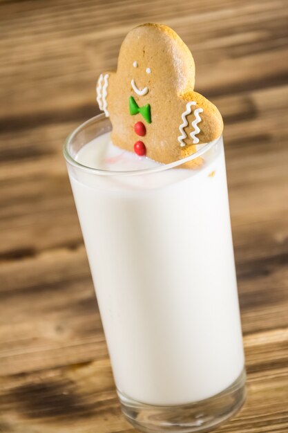 Lebkuchenmann im Glas Milch auf dunklem Holztisch. Weihnachtskonzept