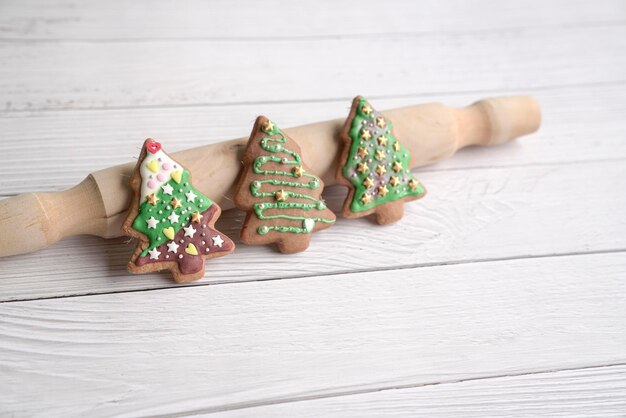 Lebkuchenplätzchen des grünen Weihnachtsbaums auf weißem hölzernem Hintergrund