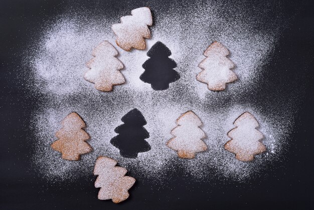 Foto lebkuchenplätzchen im puderzucker auf einem schwarzen hintergrund