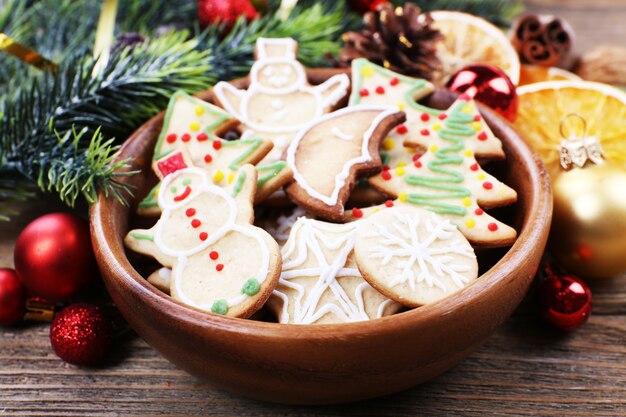 Lebkuchenplätzchen in Schüssel mit Weihnachtsdekoration auf Holztischhintergrund