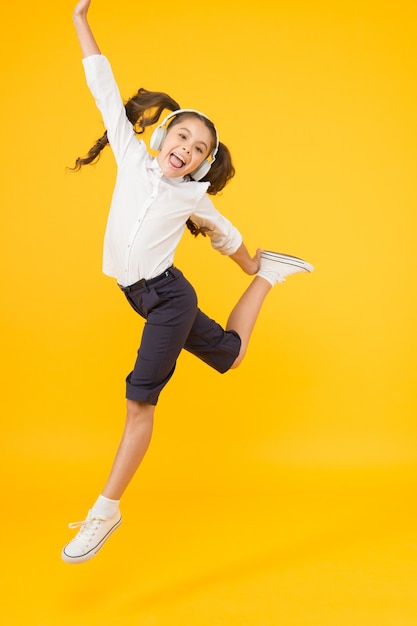 Lección de baile. El niño disfruta del sonido de la música. Educación de audio. Educación en casa. Auriculares de pupila de niña pequeña. Niño feliz escucha música. Cantar la canción. Audio libro. Concepto de educación y diversión. Educación en línea.