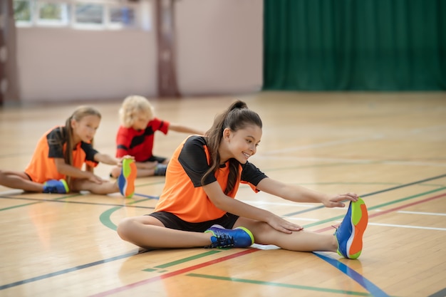 Leccion de educación fisica. Tres niños en ropa deportiva brillante con lección de educación física