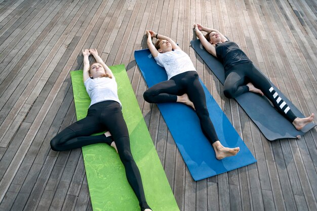 Lección de entrenamiento para relajar el cuerpo y calmar la mente en Park Grupo de mujeres jóvenes practicando yoga