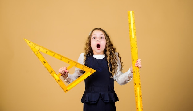 Foto lección de matemáticas educación y conocimiento disciplinas escolares stem alumna con grandes reglas niña pequeña regreso a la escuela estudiante de escuela aprendiendo geometría me encantan las matemáticas matemáticas maravillosas