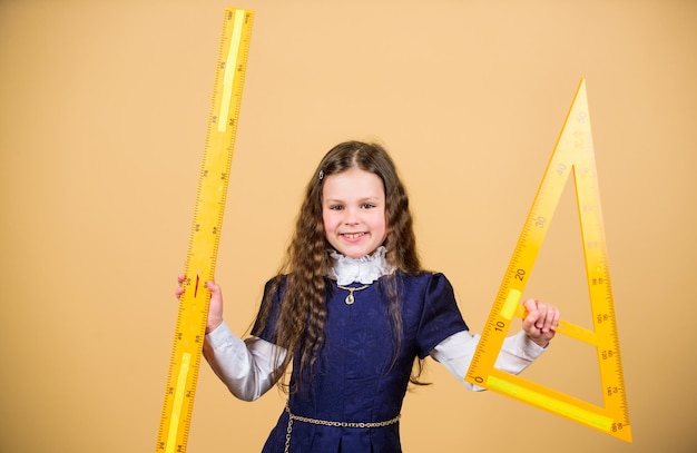 Lección de matemáticas Educación y conocimiento Estudiante de escuela aprendiendo geometría STEM disciplinas escolares niña pequeña regreso a la escuela Alumna niña con grandes reglas Día del maestro