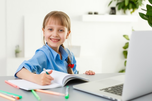 Lecciones remotas. El niño sonríe feliz y obtiene conocimientos de forma remota. Niña estudia aprendizaje en línea desde casa. Escuela en línea.