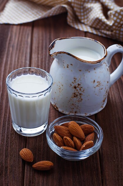 Leche de almendras y almendras sobre fondo de madera.