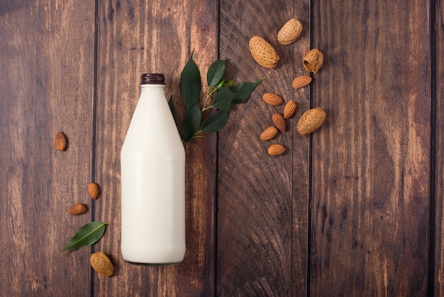 Leche de almendras a base de plantas, bebida alternativa saludable en botella en madera, ingredientes para leche de plantas