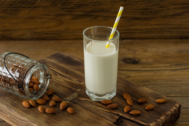 Leche de almendras en vaso con almendras sobre mesa de madera.