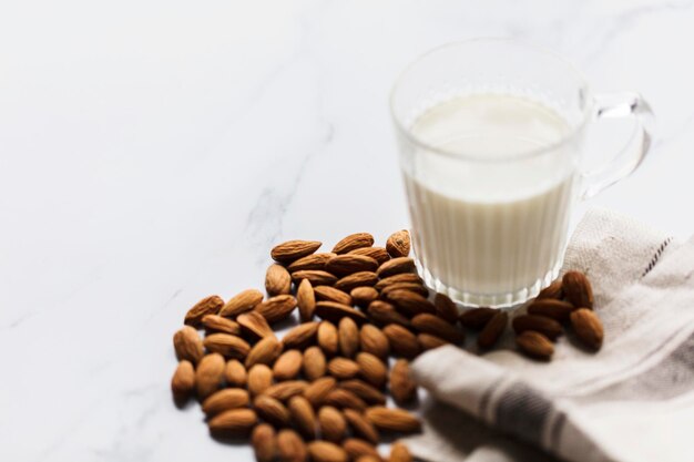 Leche de almendras en un vaso rodeado de almendras orgánicas