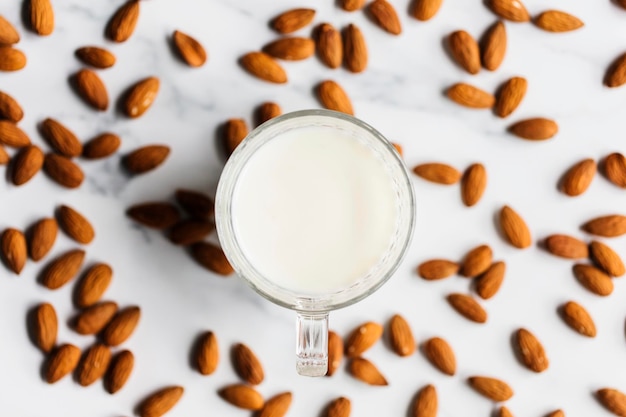 Leche de almendras en un vaso rodeado de almendras orgánicas