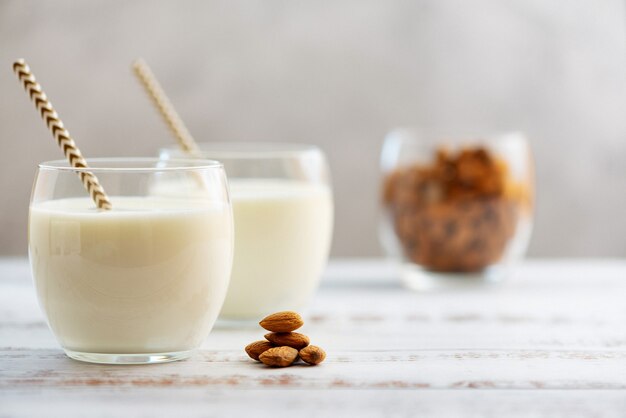 Leche de almendras en vasos con almendras sobre una mesa de madera clara.