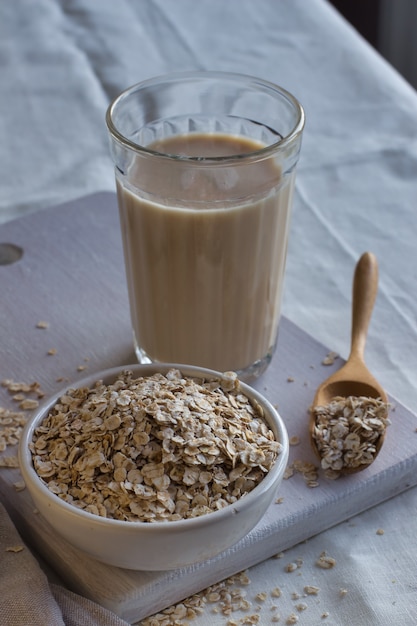 Foto leche de avena y avena sobre un fondo claro.