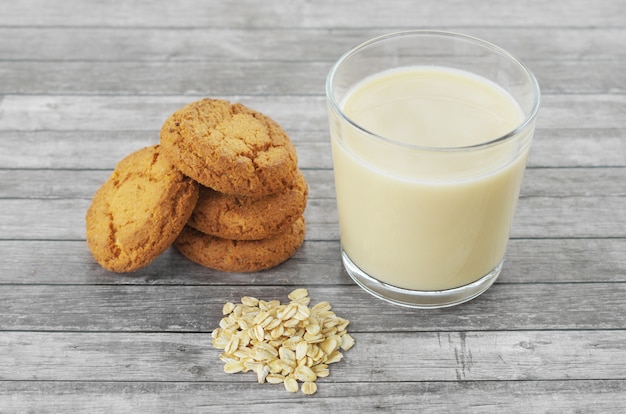 Leche de avena en un vaso con galletas y copos de avena