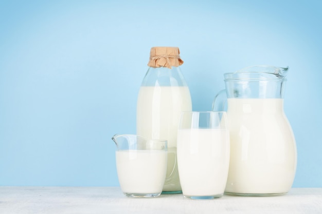 Leche en botella y vaso frente a fondo azul con espacio para copiar