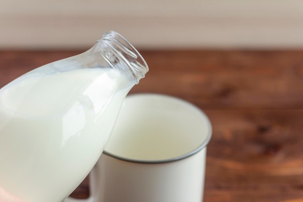 Foto la leche de la botella se vierte en una taza.