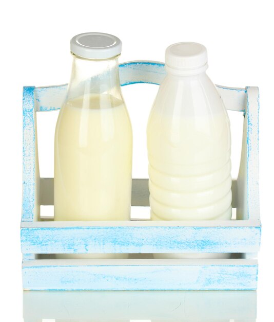 Leche en botellas en caja de madera aislada en blanco