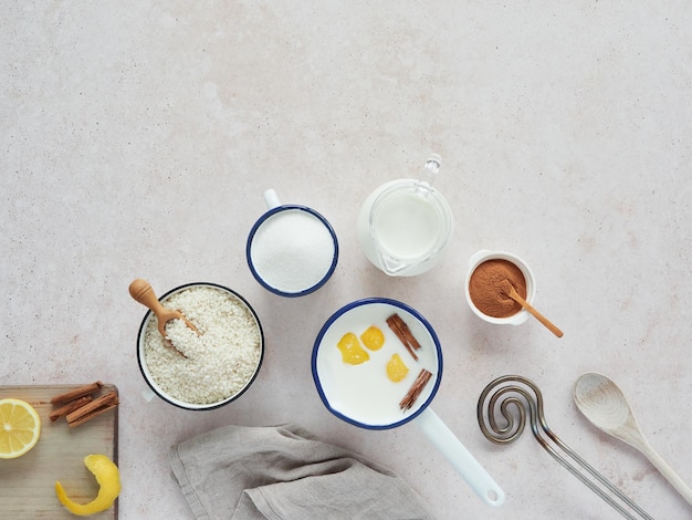 Leche con canela y limón en una cacerola e ingredientes para preparar la receta de arroz con leche