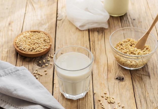 Leche de cebada en vaso sobre la mesa de madera con ingredientes