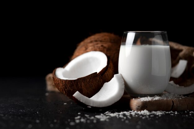 Leche de coco fresca en un vaso contra un fondo oscuro