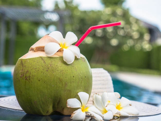 La leche de coco con tubo y piscina en el fondo.