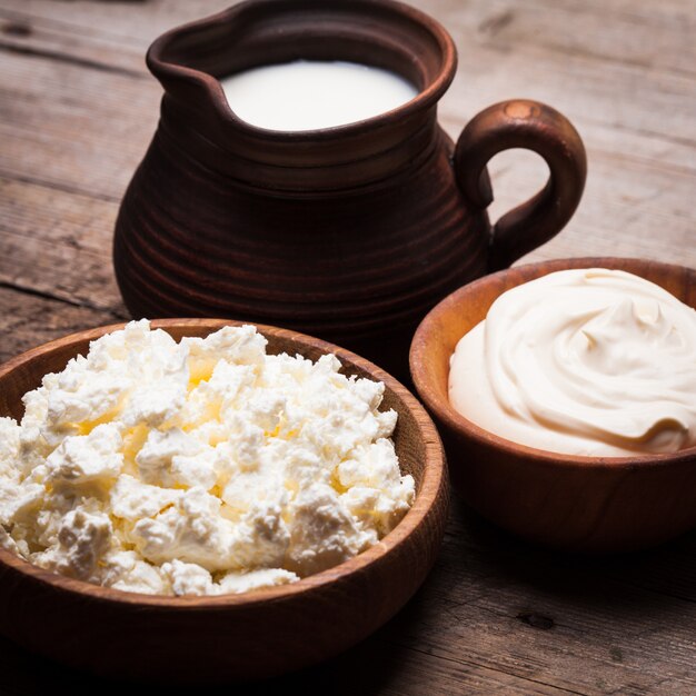 Leche, crema agria y cuajada sobre una tabla rústica de madera