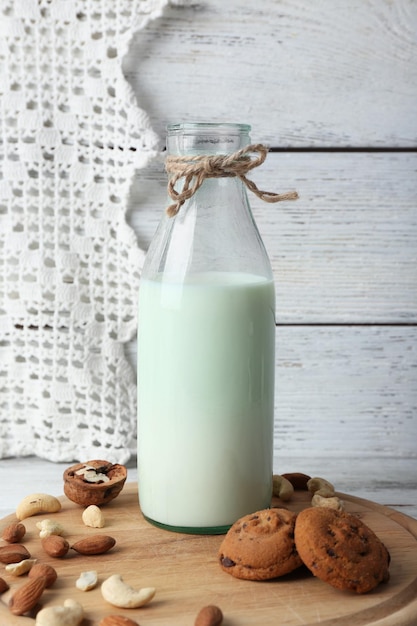 Leche en cristalería con nueces y galletas sobre fondo de madera