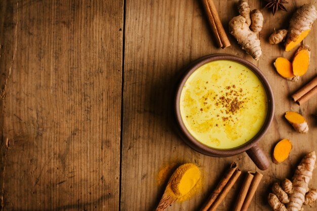 Leche de cúrcuma caliente con especias en la mesa de madera