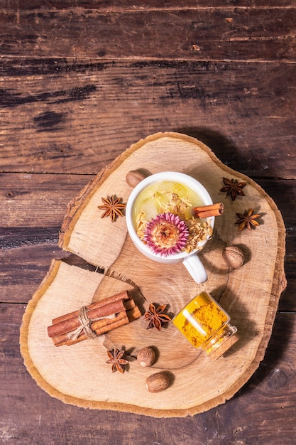 Leche de cúrcuma dorada con hielo. Especias de canela, nuez moscada, anís. Concepto de bebida de desayuno saludable por la mañana. Una moderna luz dura, sombra oscura, mesa de madera vieja, espacio de copia