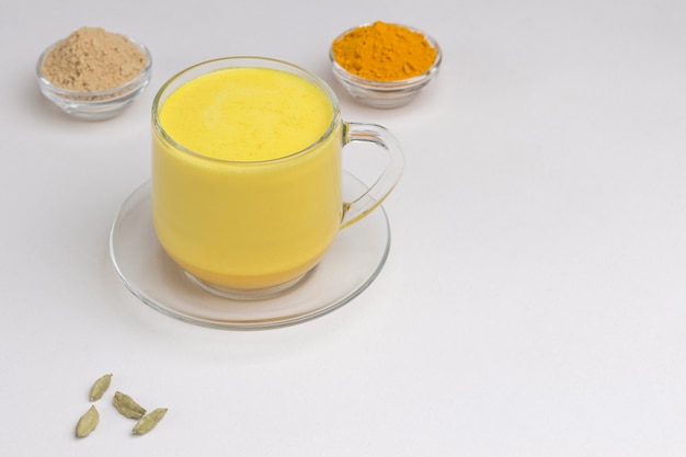Leche dorada de cúrcuma india en vaso con ingredientes para cocinar