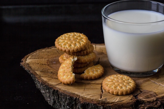 Leche fresca y saludable en taza y pila de galletas sobre fondo negro