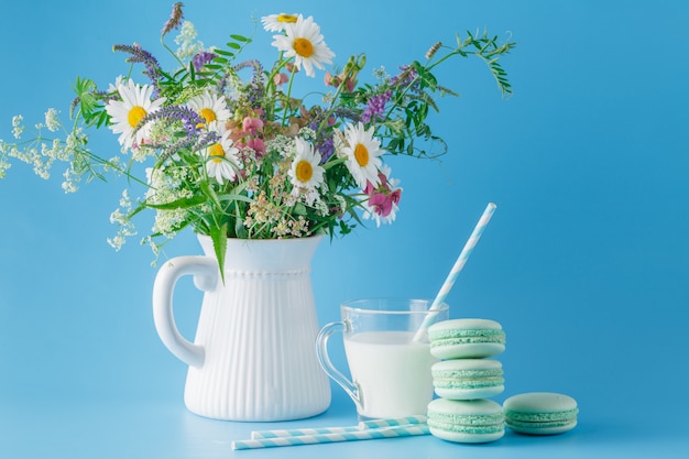 Leche fresca en taza de vidrio y flores silvestres