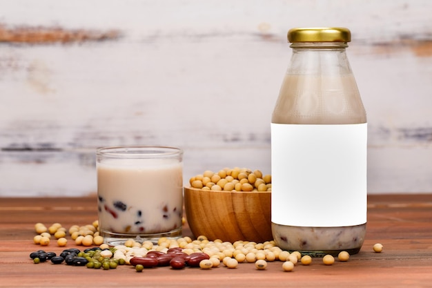 Leche de frijoles saludables de desayuno vegetariano para nutrición y bebida refrescante mezclada con granos de legumbres orgánicas naturales. Extracto líquido en vaso y botella de vidrio como bebida publicitaria.